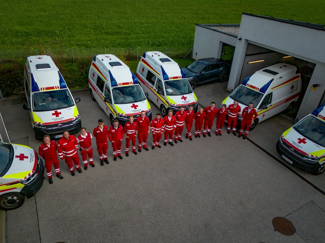 Luftbild: Rettungsfahrzeuge und Mannschaft des Roten Kreuzes in Aufstellung vor der Dienststelle