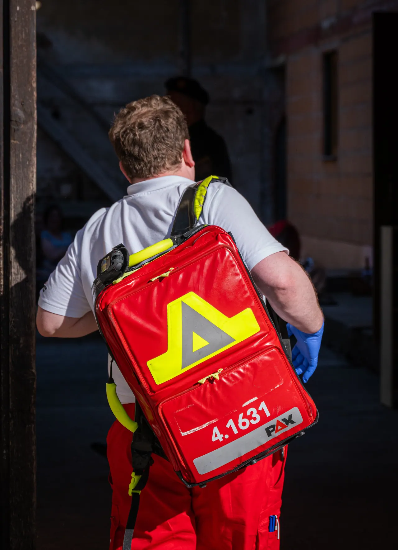 Sanitäter mit rotem Notfallrucksack von hinten beim Betreten eines Gebäudes
