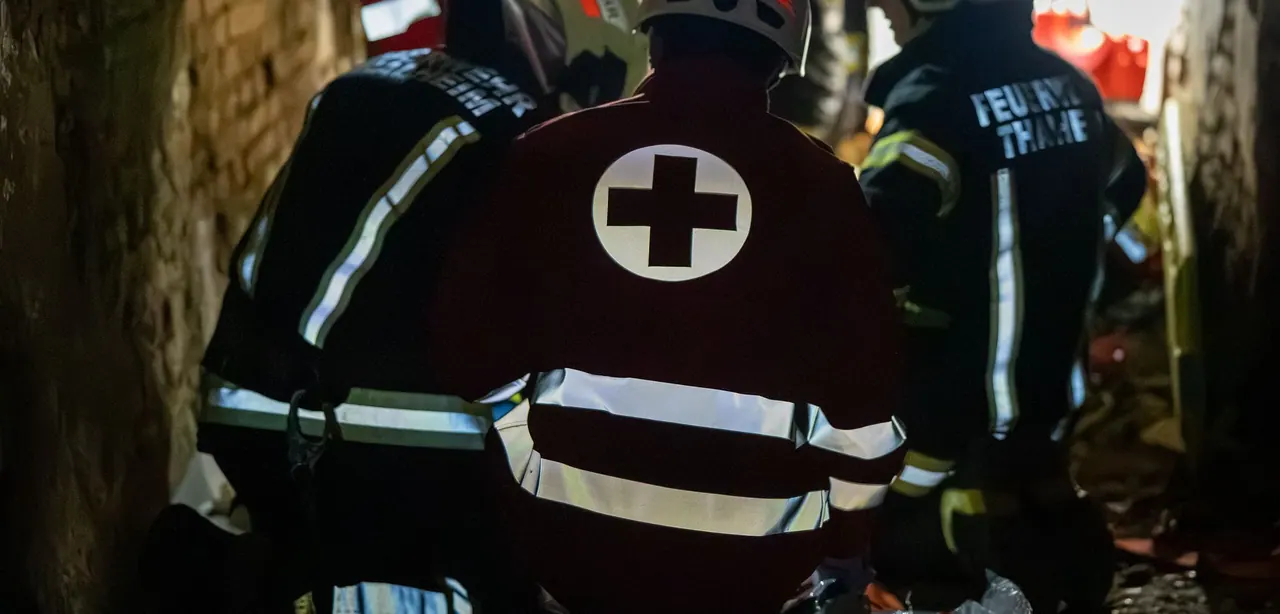 Einsatzkräfte von Rotem Kreuz und Feuerwehr von hinten bei einer Übung in einem engen Gewölbe
